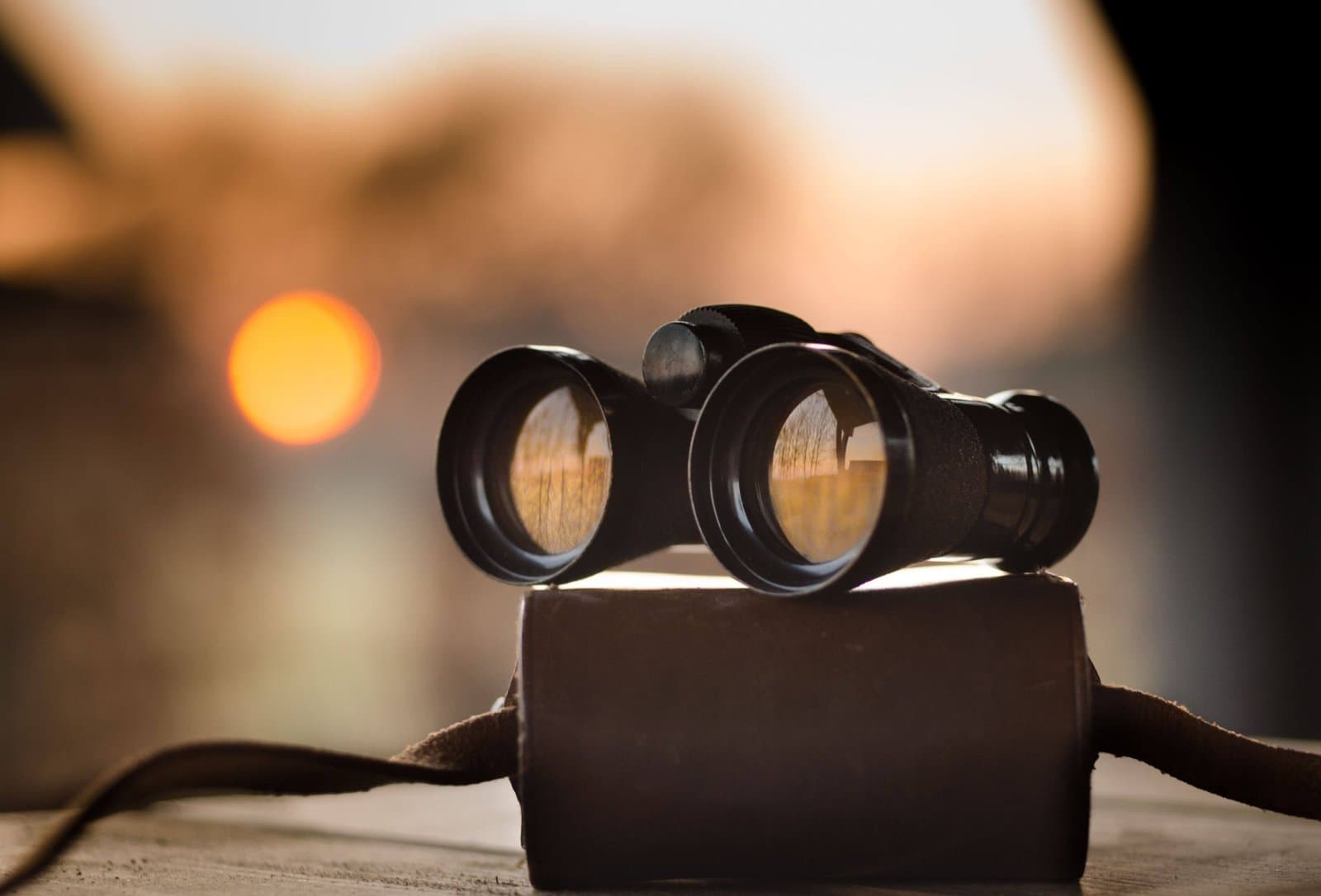 A pair of binoculars resting on a case at sunset