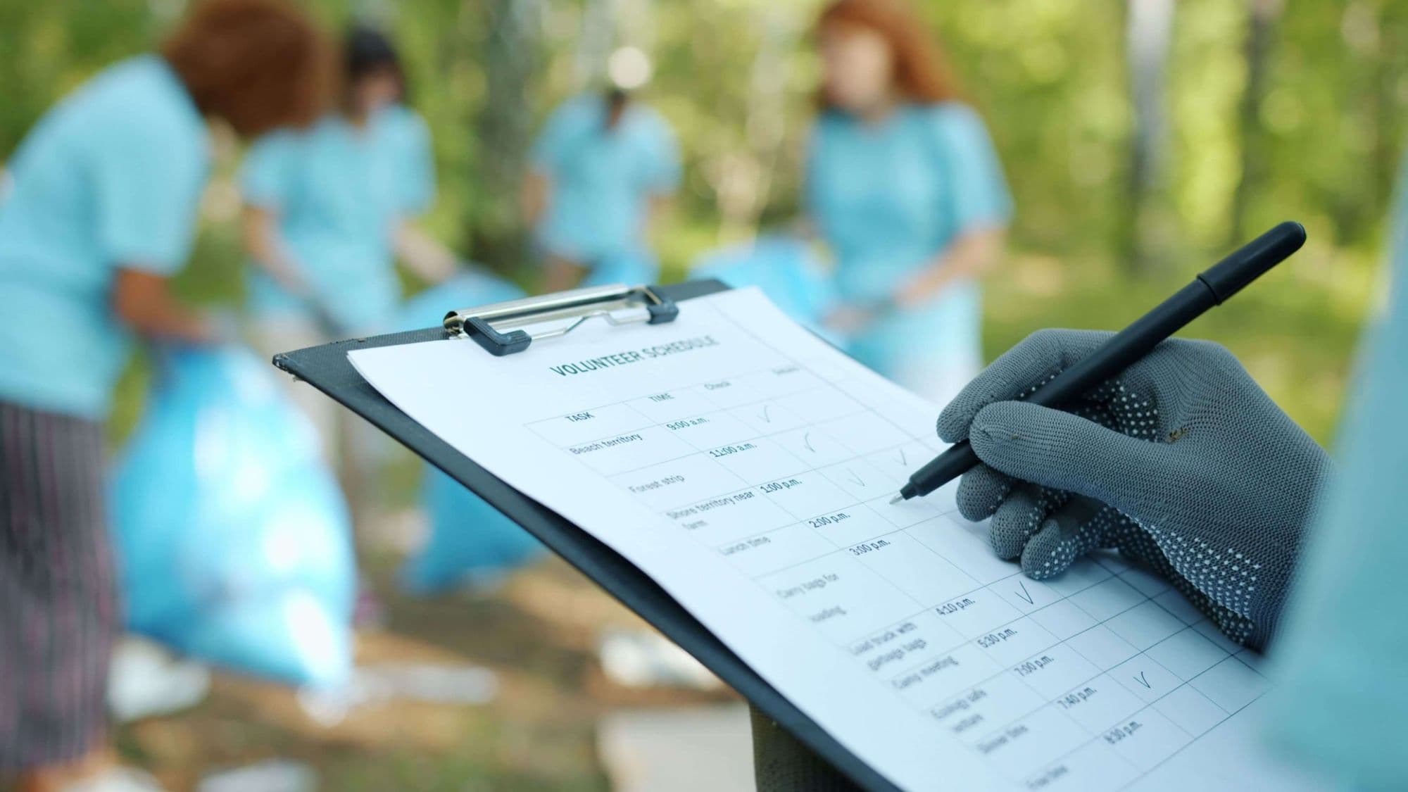 A volunteer ticking off tasks on a volunteer schedule while others work in the background